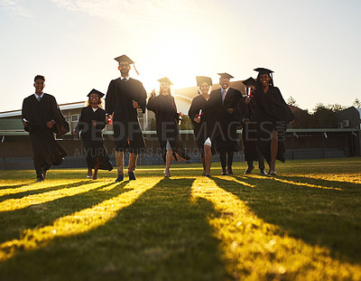 Buy stock photo Shot of a group of university students running after being graduated