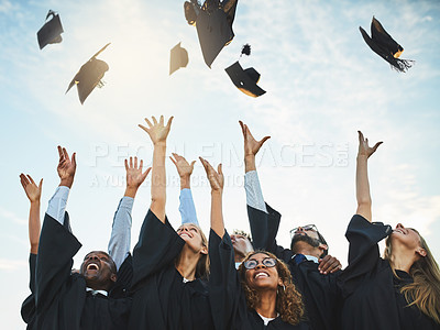 Buy stock photo Shot of a group of smiling university students cheering and throwing their caps outside on graduation day