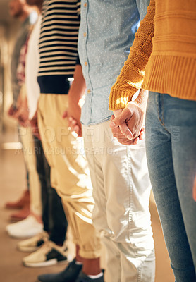 Buy stock photo Shot of a diverse group of people holding hands while standing in a line
