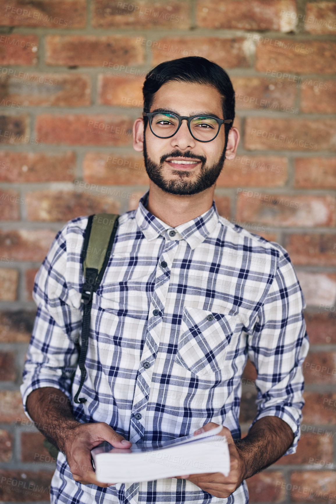 Buy stock photo Cropped shot of a handsome young male university student standing outside against a facebrick wall