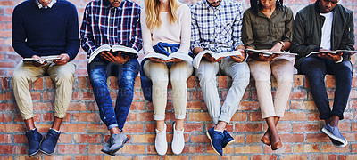 Buy stock photo Cropped shot of a group of unrecognizable university students studying while sitting outside on a facebrick wall