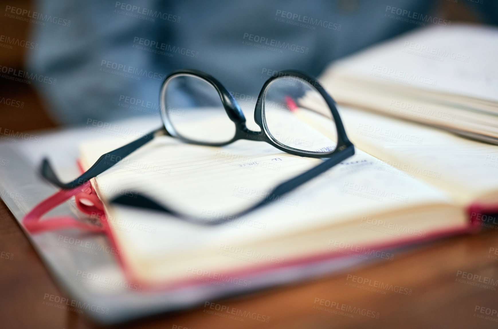 Buy stock photo Closeup shot of reading glasses on an open book on a university desk indoors