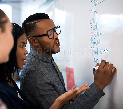 Buy stock photo Shot of a group of students brainstorming at a whiteboard in class
