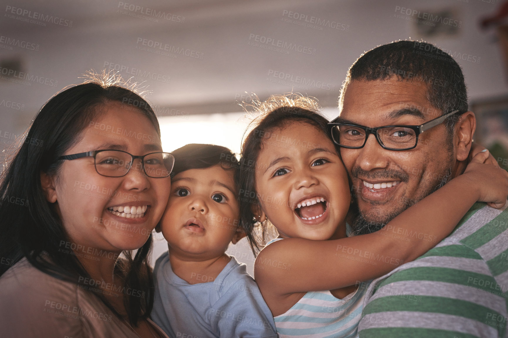 Buy stock photo Portrait, laugh and happy family hug in a living room, excited and bonding in their home together. Face, children and parents in a lounge embrace, relax and laughing at funny, comedy and crazy joke