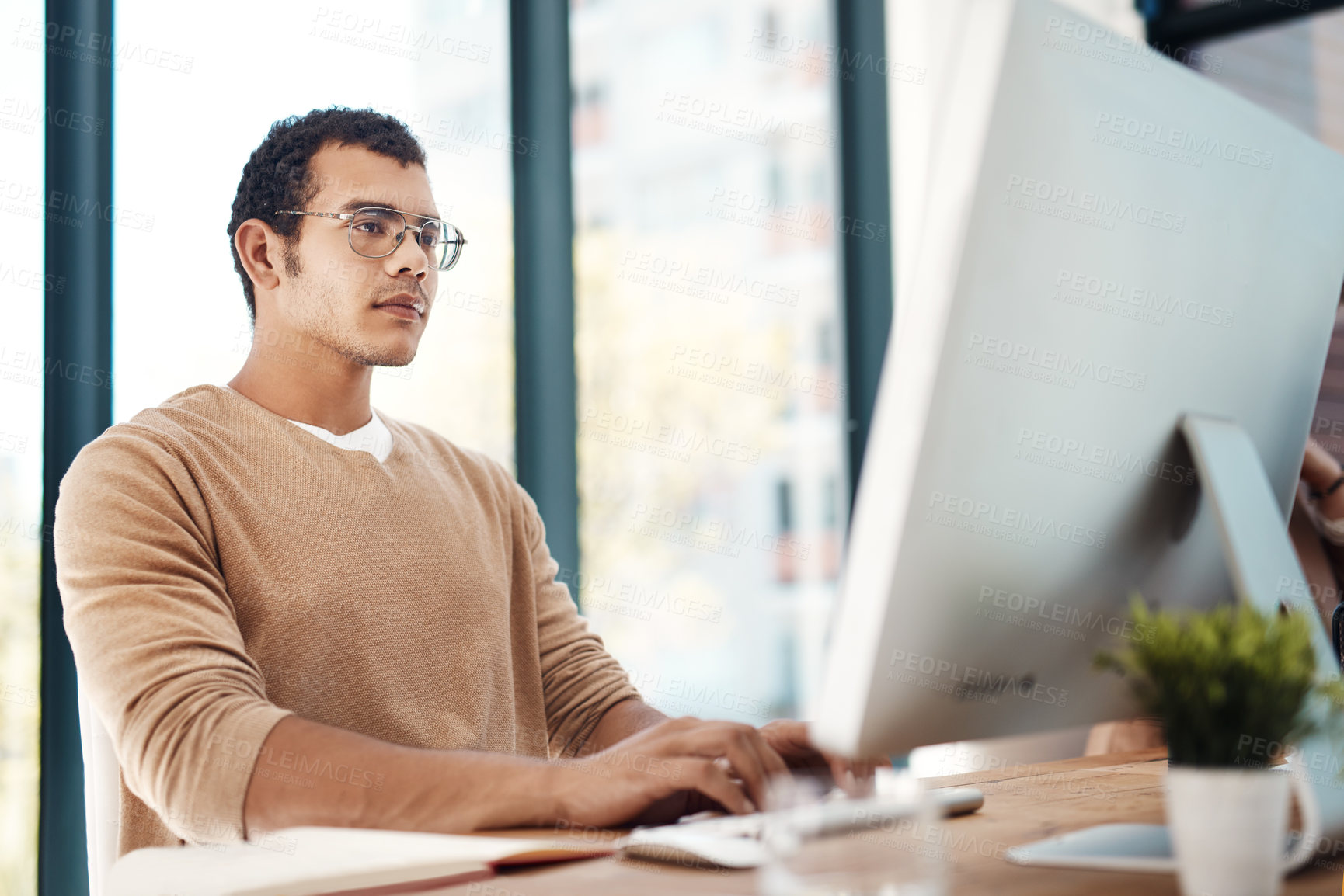 Buy stock photo Shot of a young designer working on a computer in an office