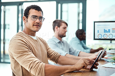Buy stock photo Portrait of a young businessman using a digital tablet with his colleagues in the background