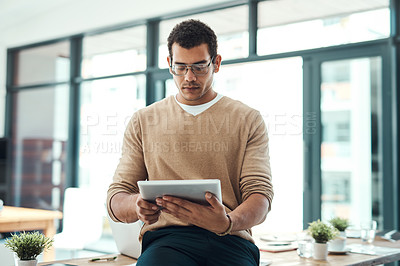 Buy stock photo Shot of a young designer working on a digital tablet in an office
