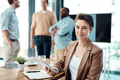 Buy stock photo Portrait of a young businesswoman using a digital tablet with her colleagues in the background