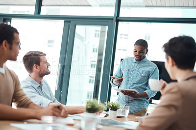 Buy stock photo Shot of a young businessman giving a presentation to his colleagues in an office