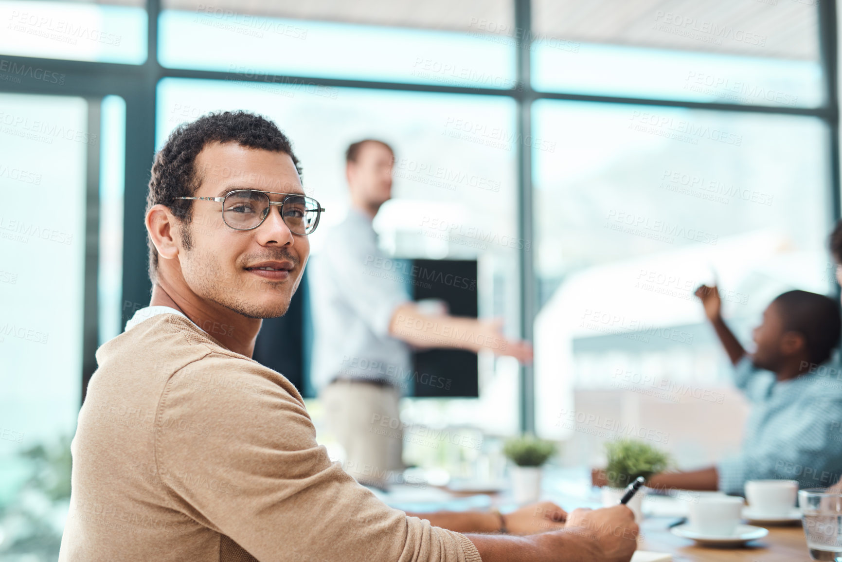 Buy stock photo Portrait of a young designer sitting in an office with his colleagues in the background