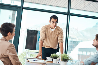 Buy stock photo Shot of a young businessman giving a presentation to his colleagues in an office