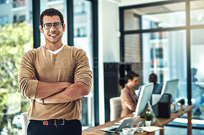 Buy stock photo Shot of a designer posing in the office with colleagues blurred in the background