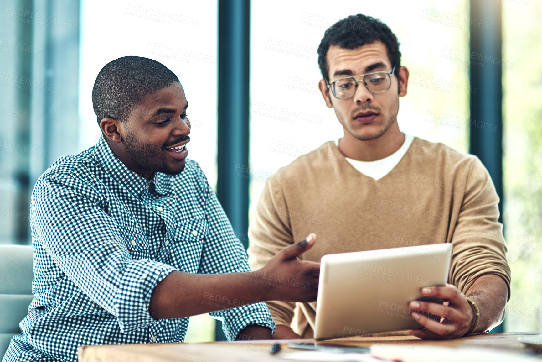 Buy stock photo Cropped shot of two young designers discussing something on a digital tablet