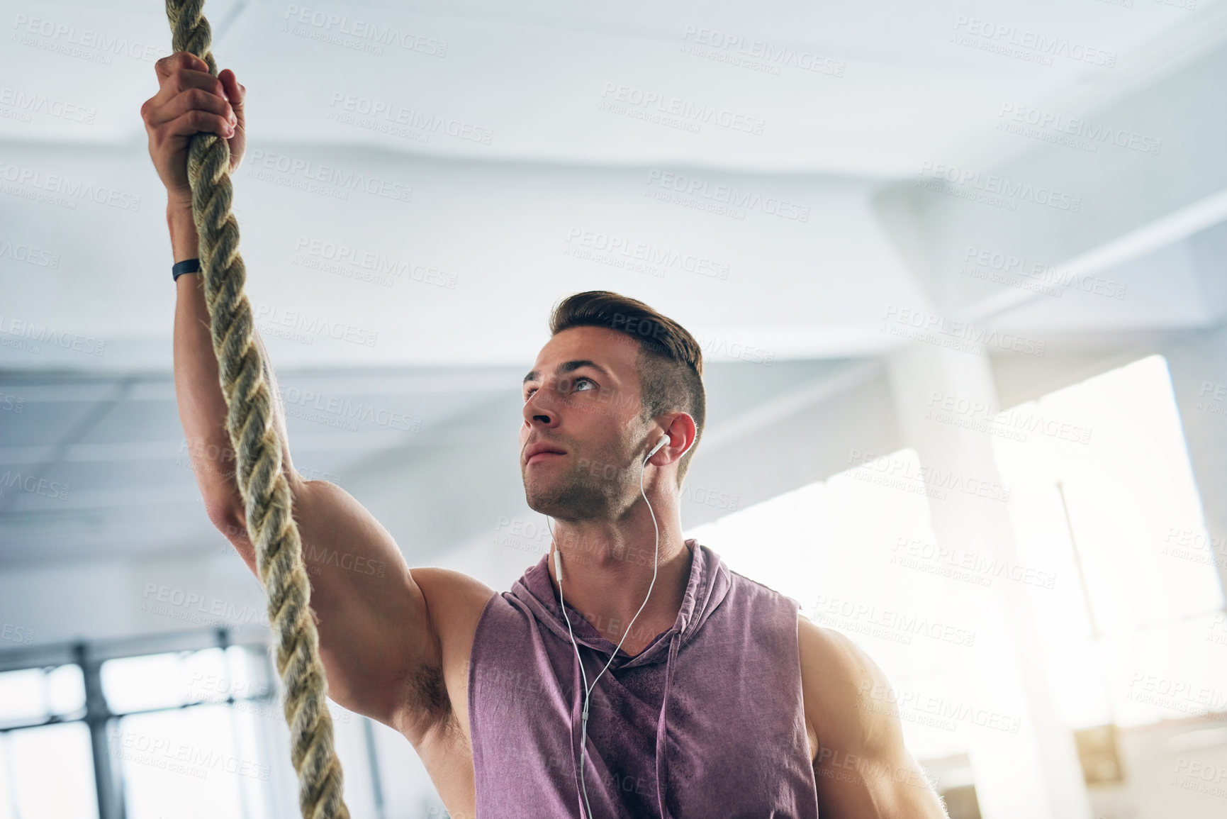Buy stock photo Shot of a muscular young man climbing a rope at the gym