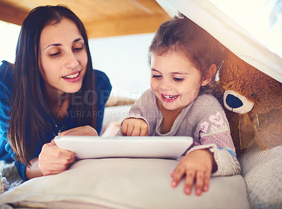 Buy stock photo Shot of a mother and her little daughter using a digital tablet together at home