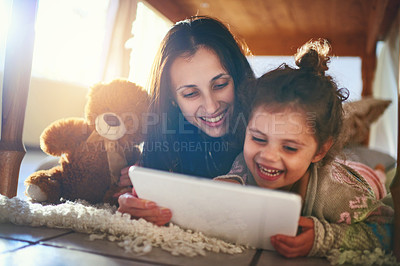 Buy stock photo Shot of a mother and her little daughter using a digital tablet together at home