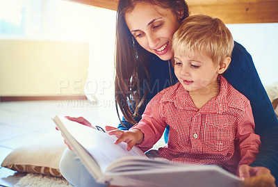 Buy stock photo Shot of a mother reading a book with her little son at home