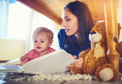 Buy stock photo Shot of a mother reading a book with her little son at home