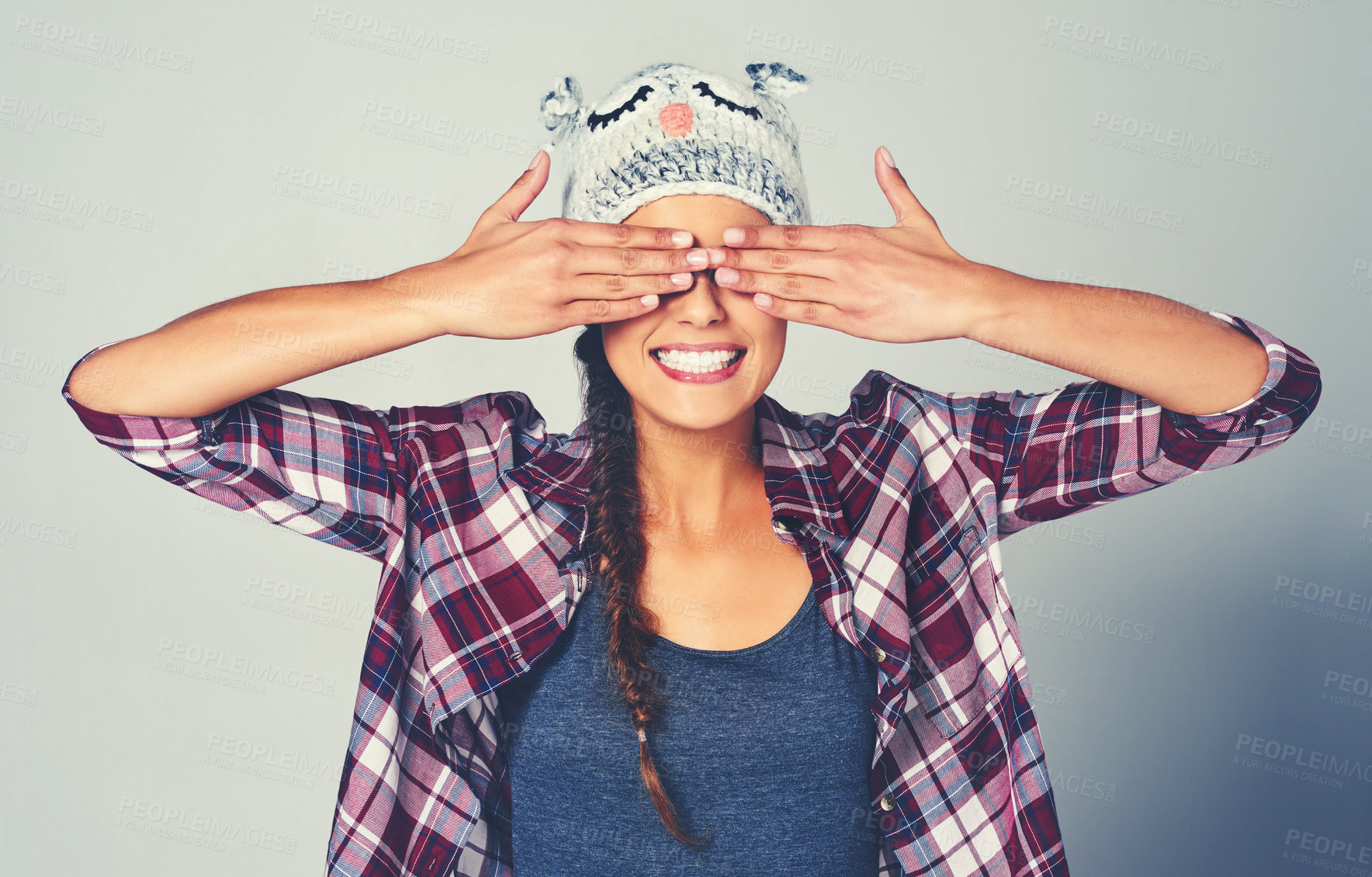 Buy stock photo Woman, cover and face with fashion in studio for playful, personality or hide and seek game. Female person, happy and hands on eyes with animal beanie for funny, silly or surprise by white background