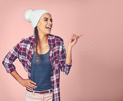 Buy stock photo Shot of an attractive young woman pointing at something against a pink background
