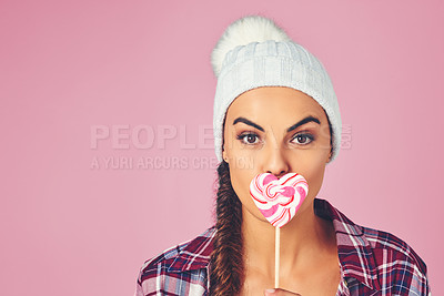 Buy stock photo Shot of a young woman holding a heart-shaped lollipop against a colorful background