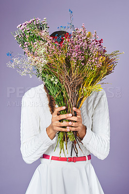 Buy stock photo Studio shot of a woman standing with a bunch of flowers in front of her face