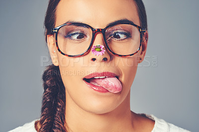 Buy stock photo Woman, glasses and goofy eye care in studio, flower and sustainable frames for optometry. Person, optical insurance and proud for eco friendly healthcare, tongue out and silly on gray background