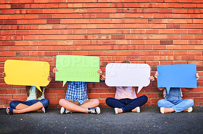 Buy stock photo Shot of a group of young children holding speech bubbles against a brick wall