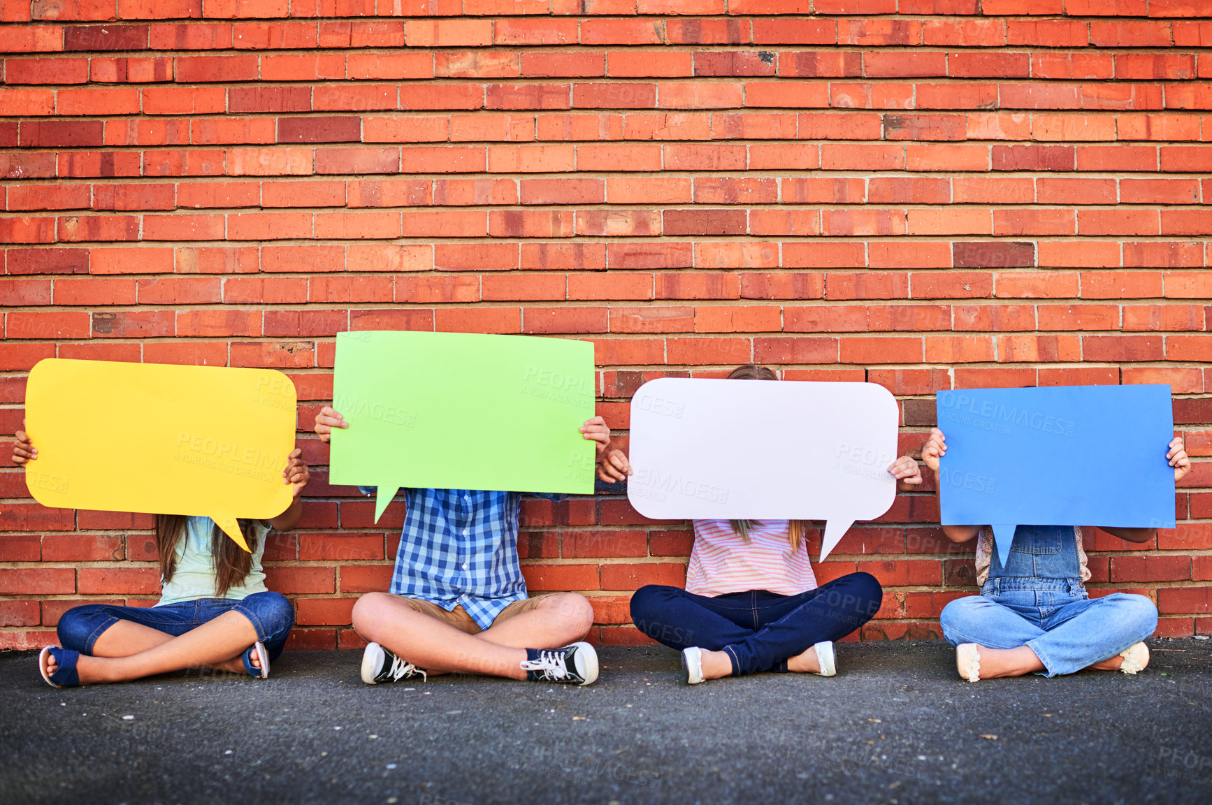 Buy stock photo Shot of a group of young children holding speech bubbles against a brick wall