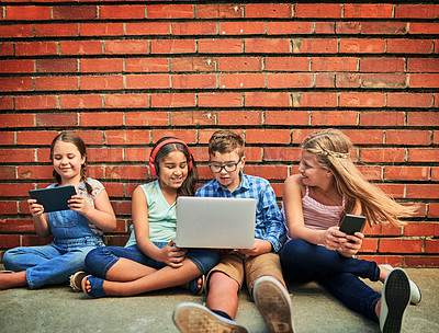 Buy stock photo Shot of a group of young children using digital devices against a brick wall