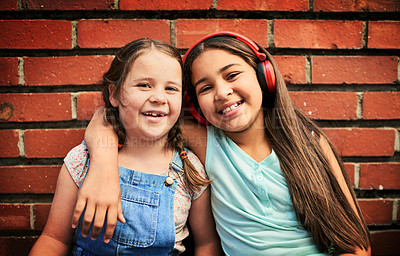 Buy stock photo Portrait of two young girls standing against a brick wall