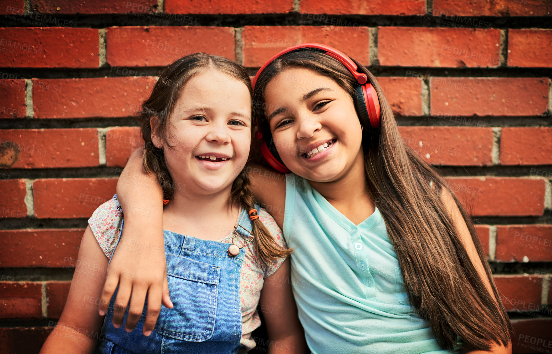 Buy stock photo Portrait of two young girls standing against a brick wall