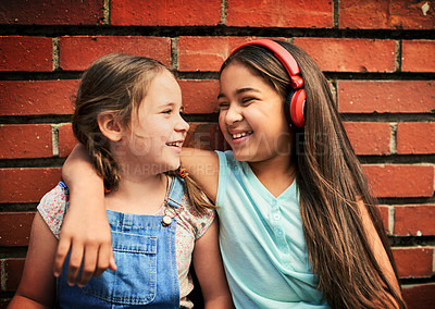 Buy stock photo Shot of two young girls standing against a brick wall