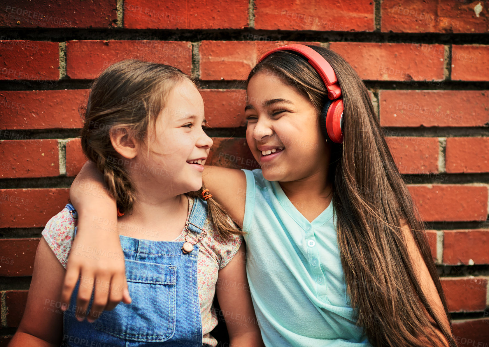 Buy stock photo Smile, headphones and children with hug by brick wall for connection, support and bonding together. Happy, girl kids and best friend with autism for childhood, comfort and positivity on weekend