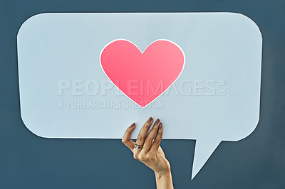 Buy stock photo Cropped studio shot of a woman holding up a speech bubble with a heart on it against a gray background