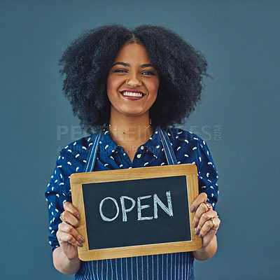 Buy stock photo Studio shot of a young woman holding a chalkboard with the word “open” on it against a gray background