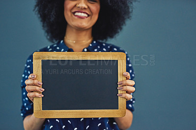 Buy stock photo Studio shot of a young woman holding a blank chalkboard against a gray background