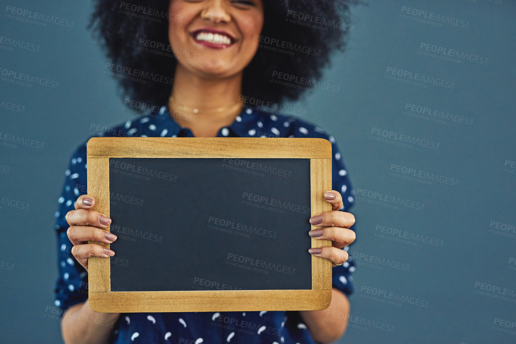 Buy stock photo Studio shot of a young woman holding a blank chalkboard against a gray background