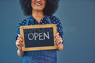 Buy stock photo Studio shot of a young woman holding a chalkboard with the word “open” on it against a gray background