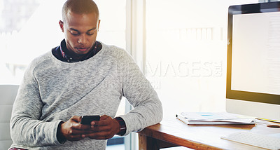 Buy stock photo Shot of a young businessman texting on his cellphone in an office