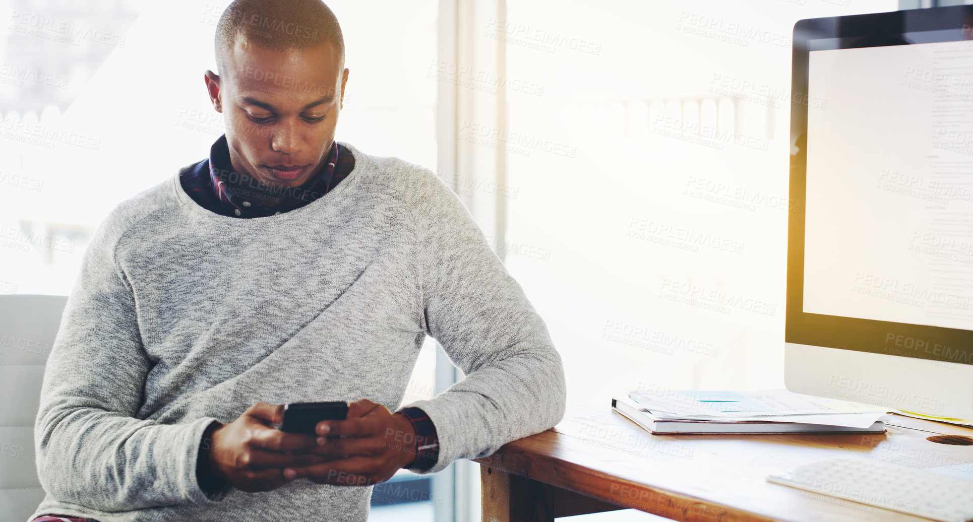 Buy stock photo Shot of a young businessman texting on his cellphone in an office