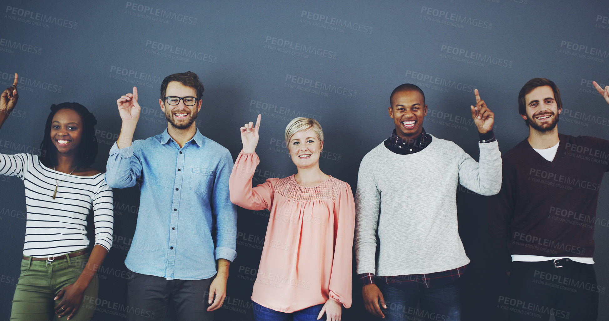 Buy stock photo Studio shot of a diverse group of people pointing upwards against a gray background