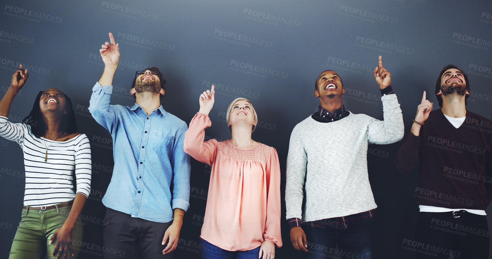 Buy stock photo Studio shot of a diverse group of people pointing upwards against a gray background