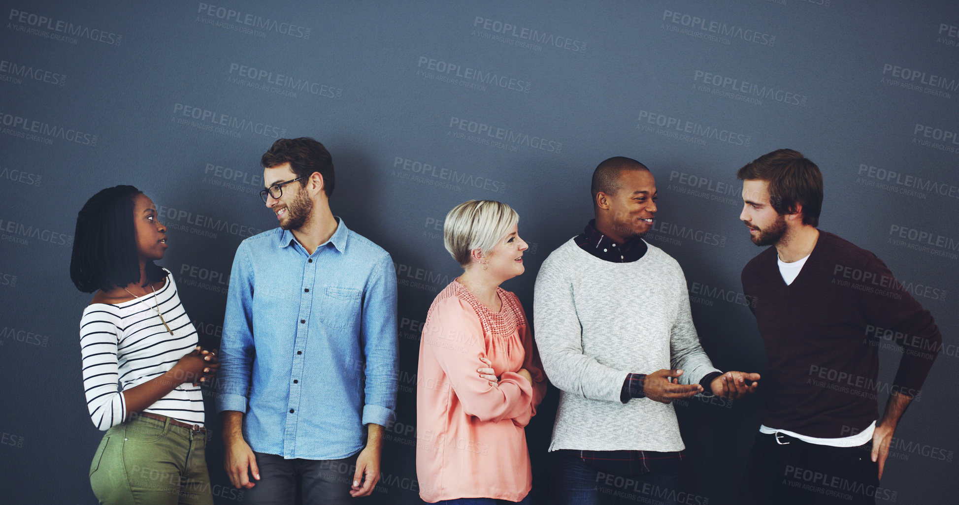 Buy stock photo Studio shot of a diverse group of people standing and chatting against a gray background