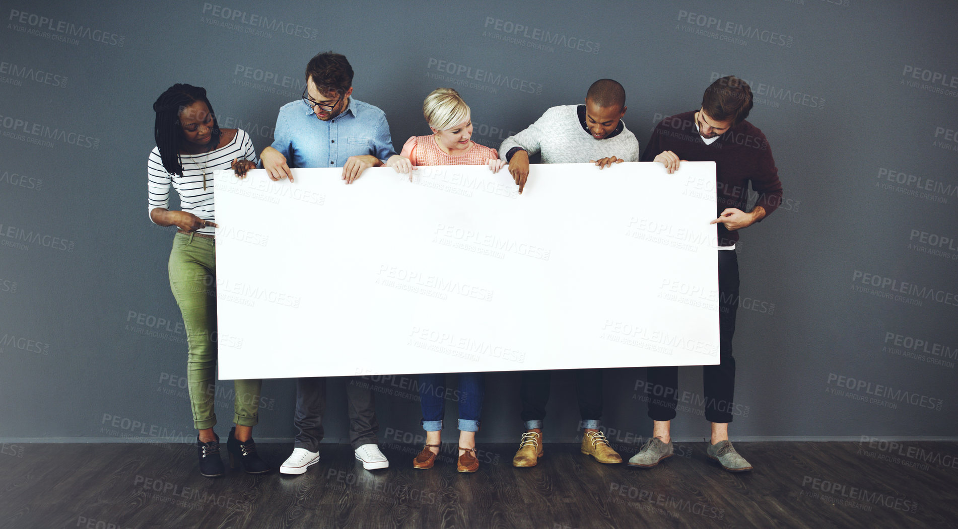 Buy stock photo Studio shot of a diverse group of people holding a blank placard against a gray background