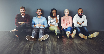 Buy stock photo Studio shot of a diverse group of people sitting together on the floor against a gray background