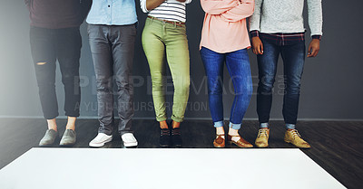 Buy stock photo Cropped studio shot of a group of people standing behind blank paper against a gray background