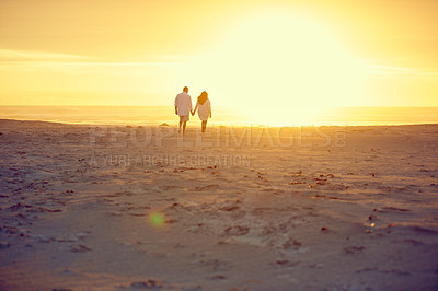 Buy stock photo Rearview shot of an affectionate mature couple walking hand in hand on the beach