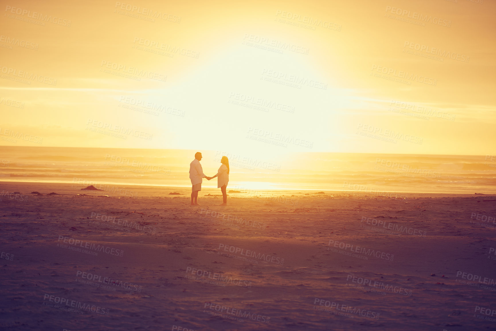 Buy stock photo Full length shot of an affectionate mature couple standing face to face and hand in hand on the beach