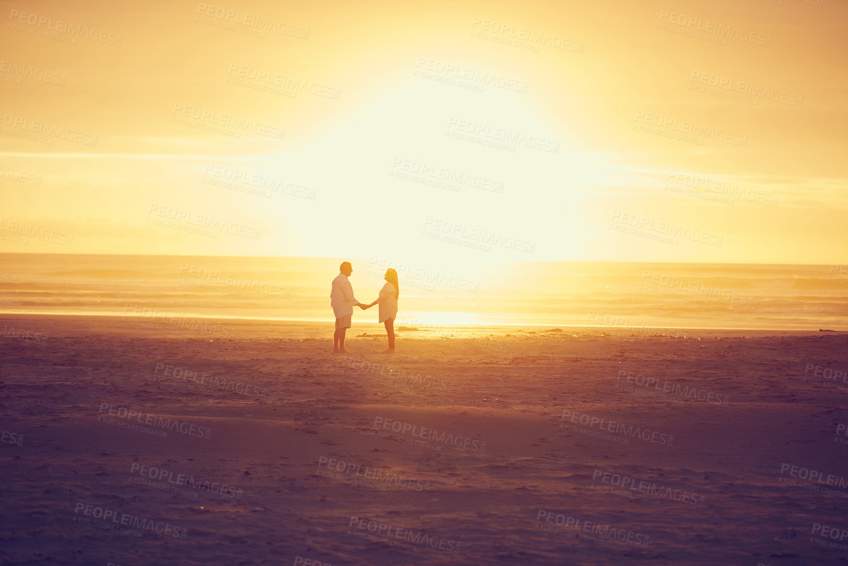 Buy stock photo Full length shot of an affectionate mature couple standing face to face and hand in hand on the beach